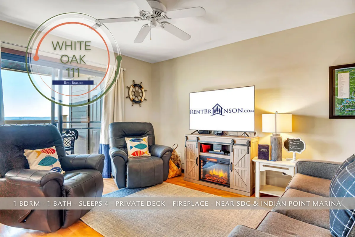 A homey living area with comfortable recliners, a wall-mounted television, a decorative electric fireplace, and tasteful wall art. The space feels inviting and ideal for entertaining or quiet nights by the fire.