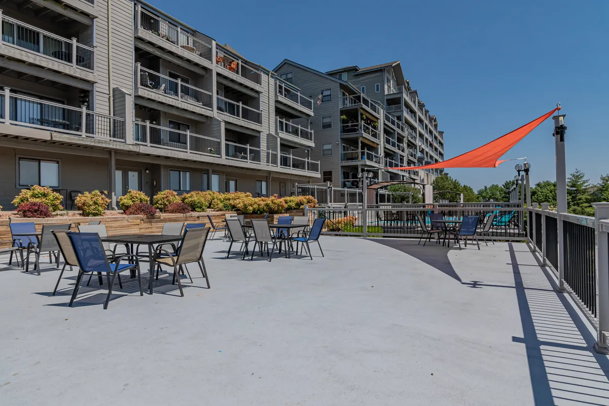 A cheerful outdoor seating area adorned with colorful flowers, with buildings visible in the background. The space is perfect for social gatherings, al fresco meals, or simply soaking up the lively ambiance of the neighborhood.