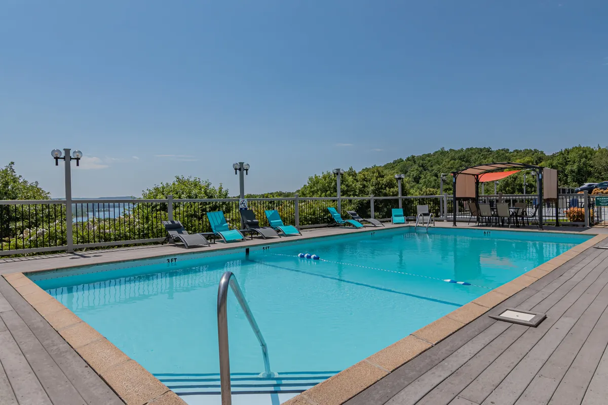 A refreshing swimming pool flanked by comfortable lounge chairs, with a canopy area providing shaded relaxation. Greenery surrounds the pool, enhancing the tranquil and rejuvenating mood of the space.