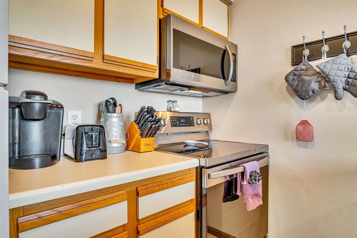 A modern kitchen featuring stainless steel appliances, a coffee maker, kitchen utensils, and dish towels. The space is designed for cooking, baking, and socializing, capturing the essence of a well-equipped culinary space. The setup is cozy yet functional, ideal for both big family meals and intimate breakfasts.