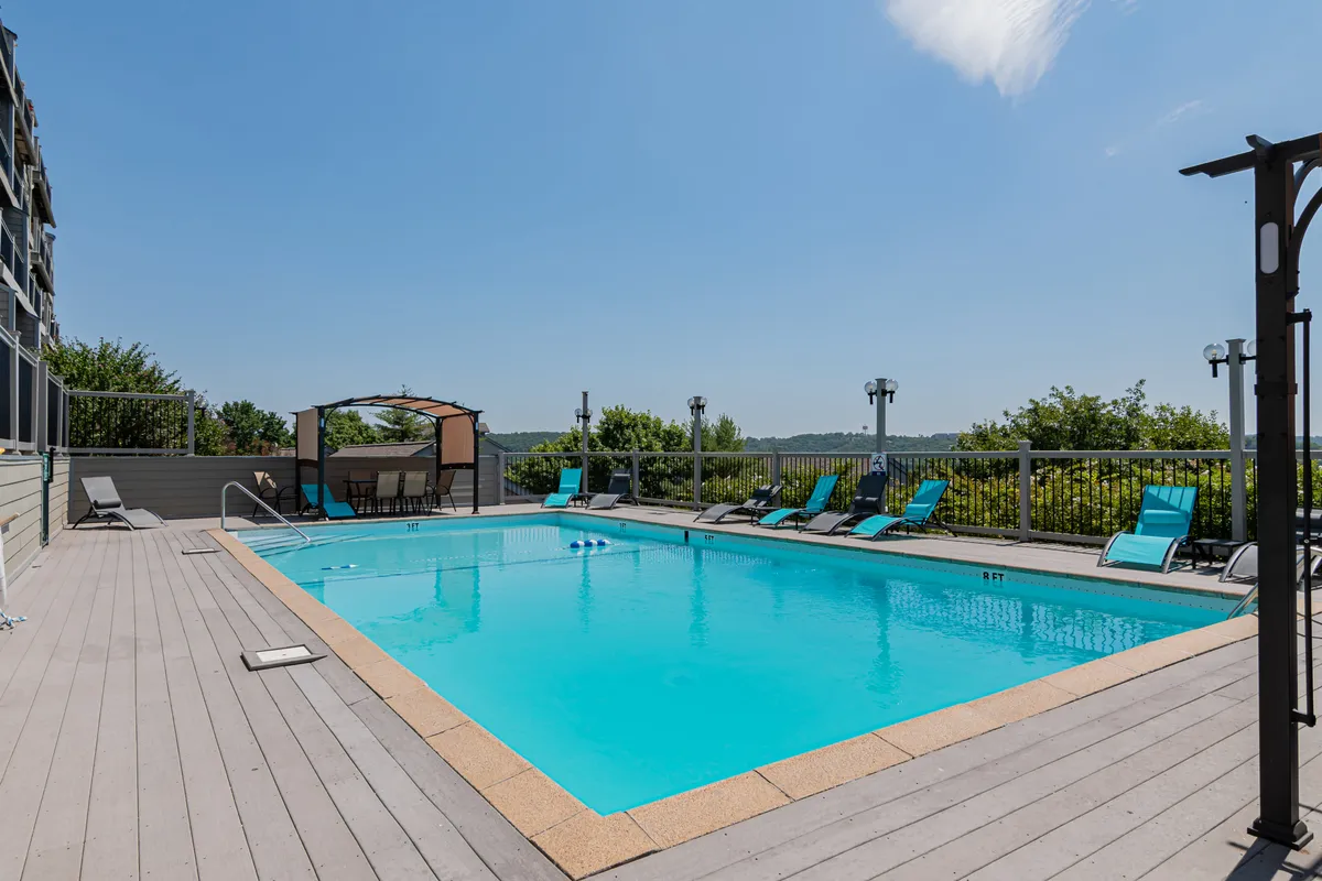 A spacious outdoor swimming pool surrounded by inviting lounge chairs and a stylish cabana, all set against a landscaped backdrop. The scene is ideal for both relaxation and social gatherings, with an atmosphere that hints at fun, sun-soaked days and tranquil evenings.