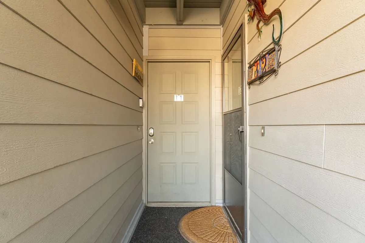 The image features the inviting entryway of the home, complete with a doormat and decorative accents. Warm lighting and thoughtful details create a welcoming first impression, underscoring the comfort and security of the property.